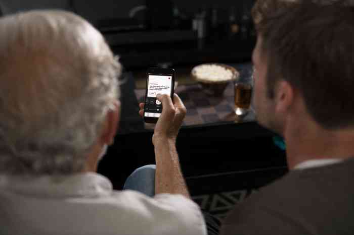 Grandfather and grandson on their sofa looking at Amplifon App on their smartphone