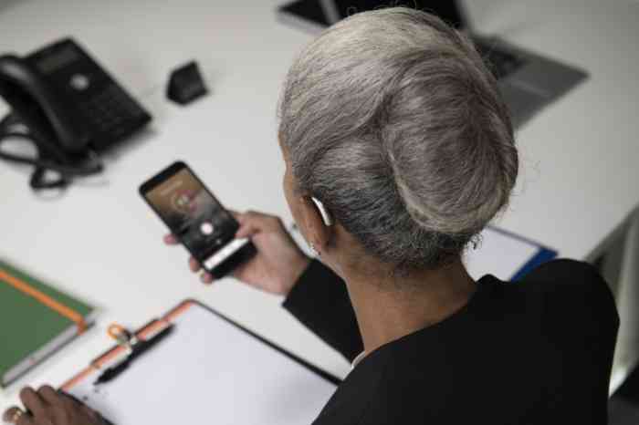 A senior woman with Behind-The-Ear hearing aid looking at Amplifon app