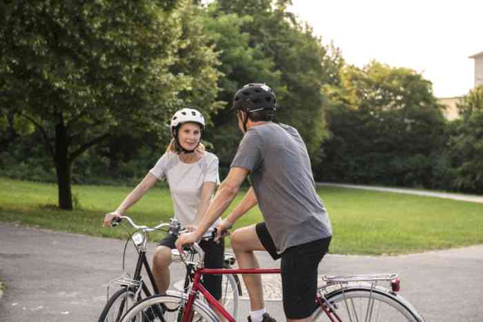 Couple with helmets talking outside on their bikes