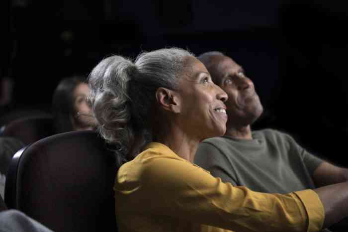 A woman enjoying a movie with her husband thanks to her almost invisible hearing aid