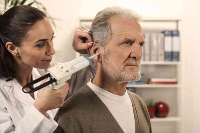 A senior man has his hearing checked by a hearing professional