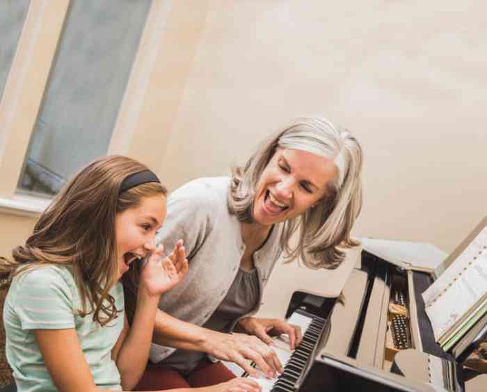 Grandmother and granddaughter laughing and playing the piano