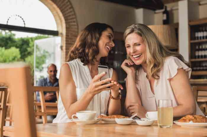 Two women laughing looking at their smartphone
