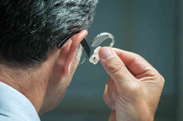 A man is watching is hearing aid