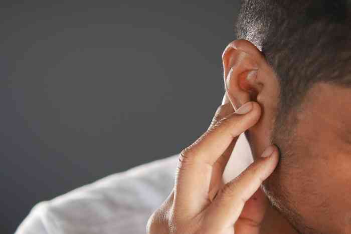 A man touching his ear.