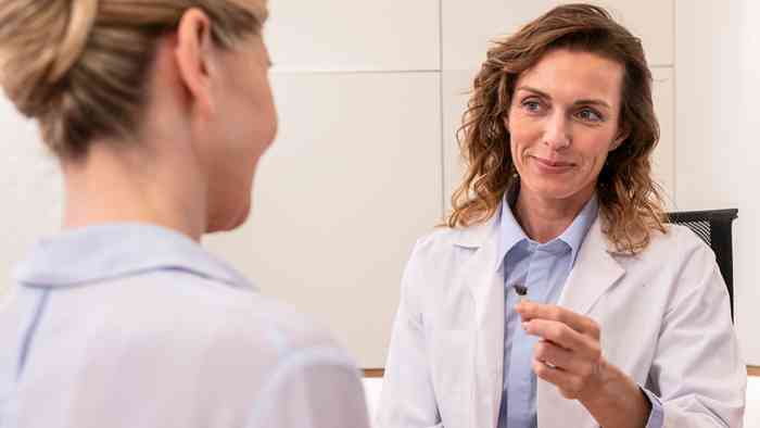 An audiologist fitting a hearing aid into a patient’s ear