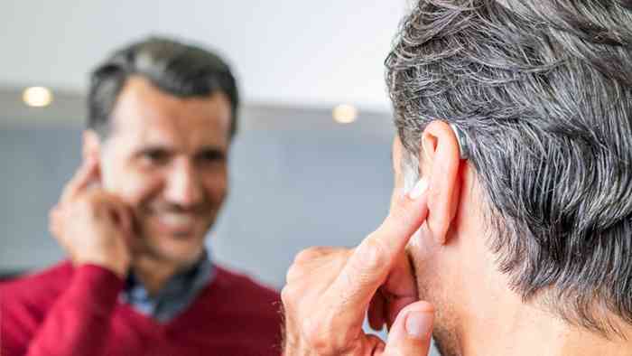 Donna sul divano che indica l’orecchio