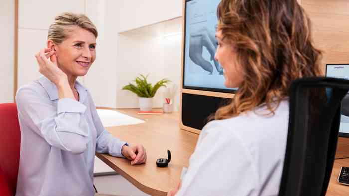 Un client homme en consultation avec une audiologiste dans un centre Amplifon