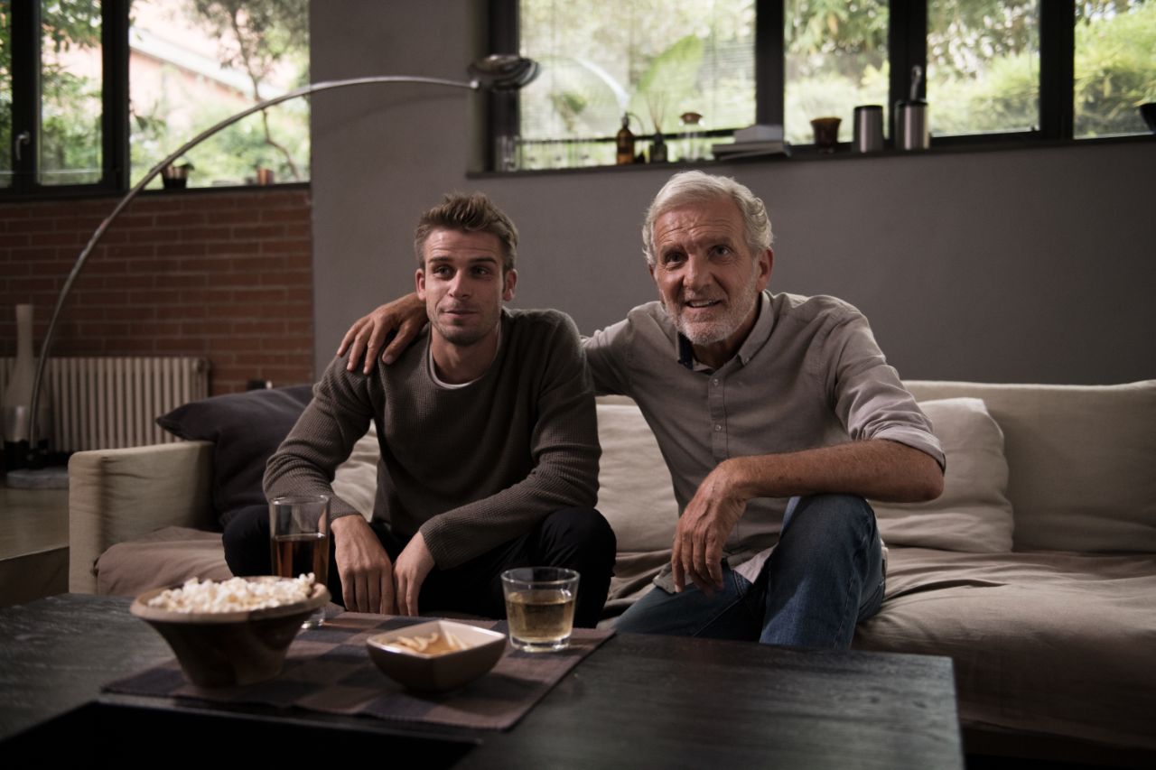 A Grandson and his Grandpa watching TV on a sofa