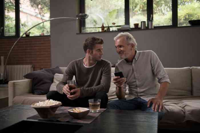 Grandfather and grandson on their sofa looking at Amplifon App on their smartphone