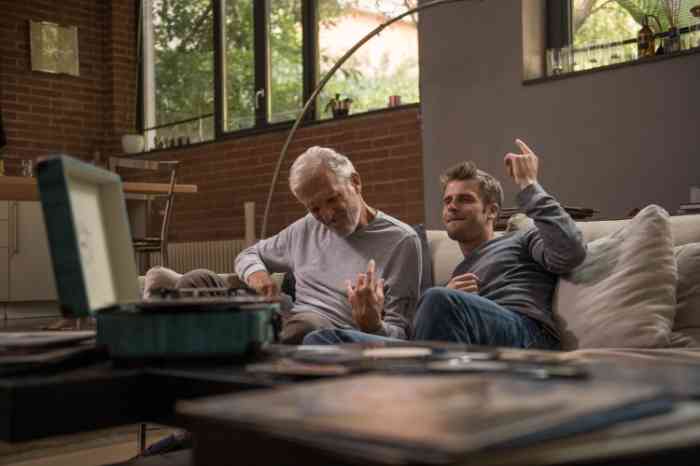 A senior and a young man listening to music on their sofa