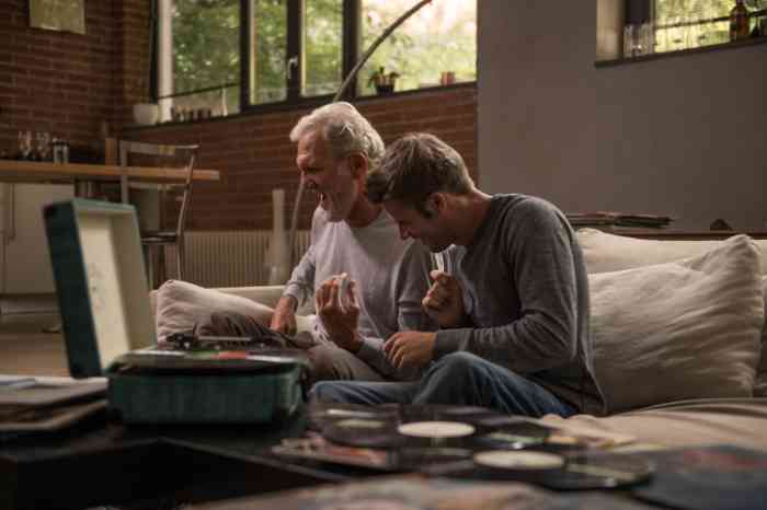 A senior and a young man listening to music on their sofa