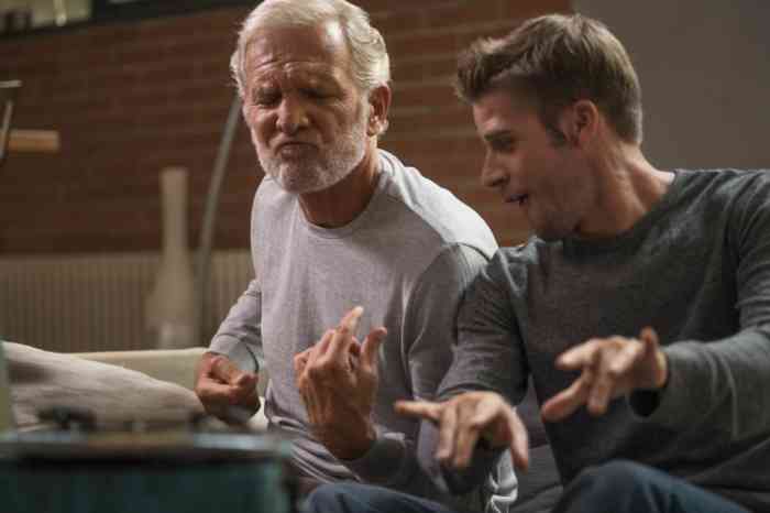 Grandfather and grandson playing air guitar on their sofa