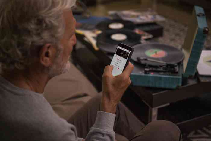 A man is checking the hearing aid's dedicated app on his smartphone