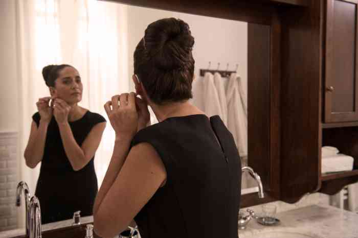 Woman with Receiver-in-the canal hearing aid looking at herself at the mirror