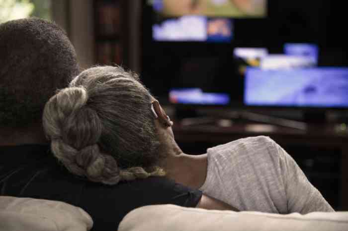 A man and a woman sitting on a sofa watching TV together
