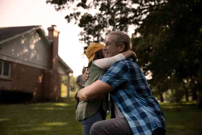 Grand-père étreignant son petit-fils portant un chapeau jaune.