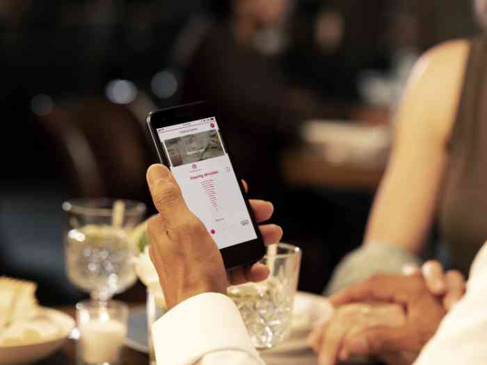 Gros plan sur la main d'un homme au restaurant consultant une application sur son smartphone.