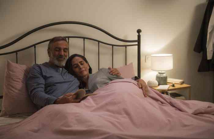 A couple lying on their bed and reading together