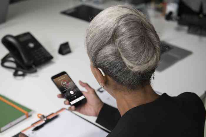 Entrepreneur with a hearing aid checking an app on her phone