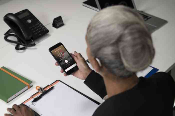 A business woman checks her hearing aid's app via smartphone