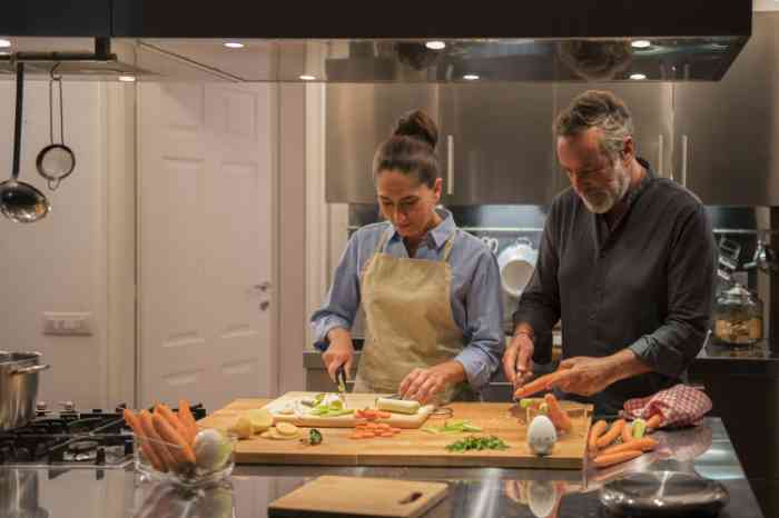 Couple chopping carrots and cooking in their kitchen