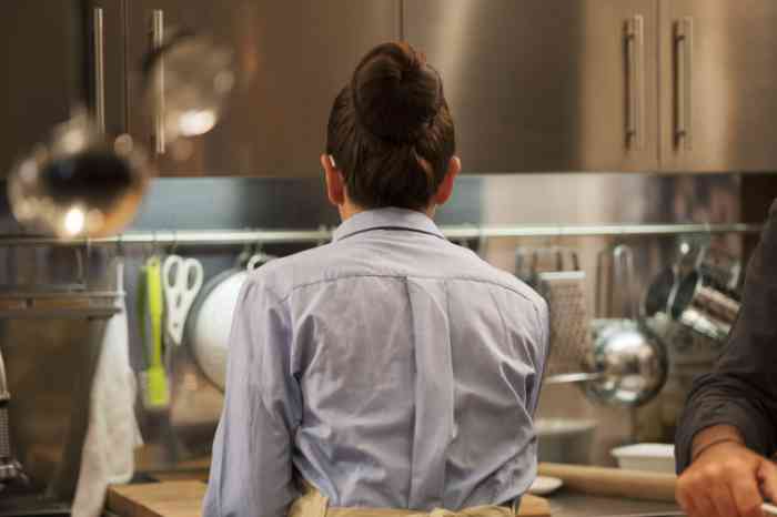 Frau mit Hörgeräten in der Küche, von hinten.