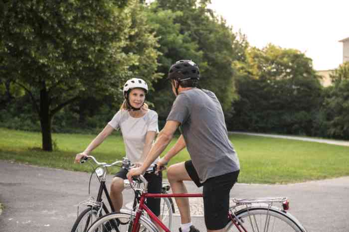 Two friends talk to each other on bikes in a park