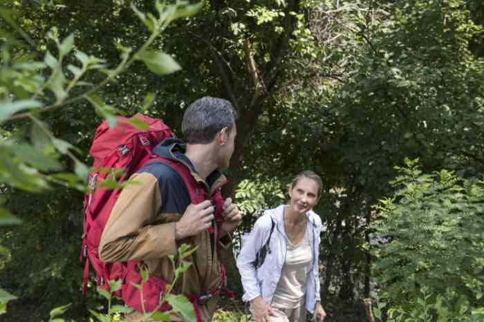 A man wearing his hearing aid and a woman walking through the trees
