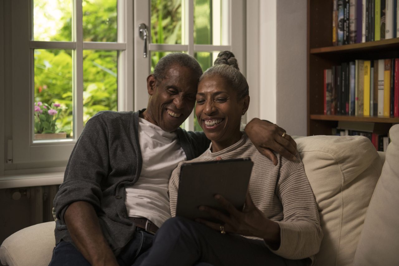Un couple assis dans un canapé avec une tablette