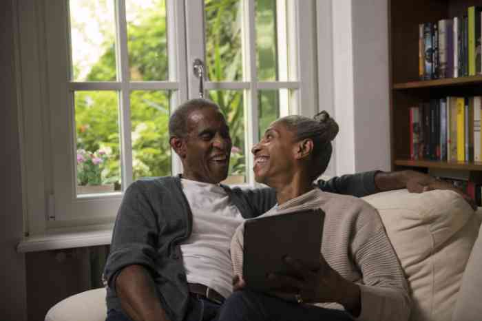 A couple with a tablet smiling on their sofa