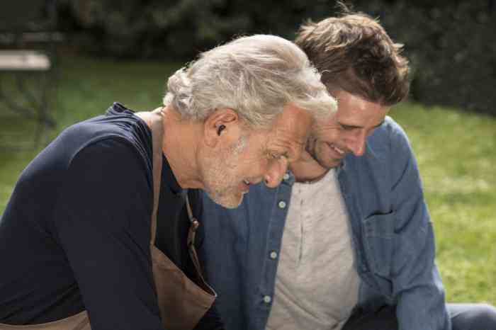 Senior man with invisible hearing aids gardening with son