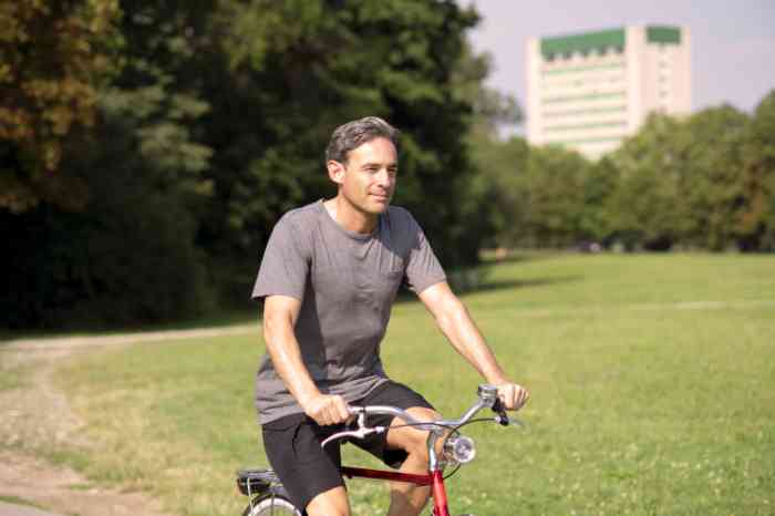 Homme vu de face faisant du vélo dans un parc.