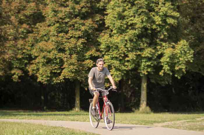 Un homme vu de face faisant du vélo dans un parc.