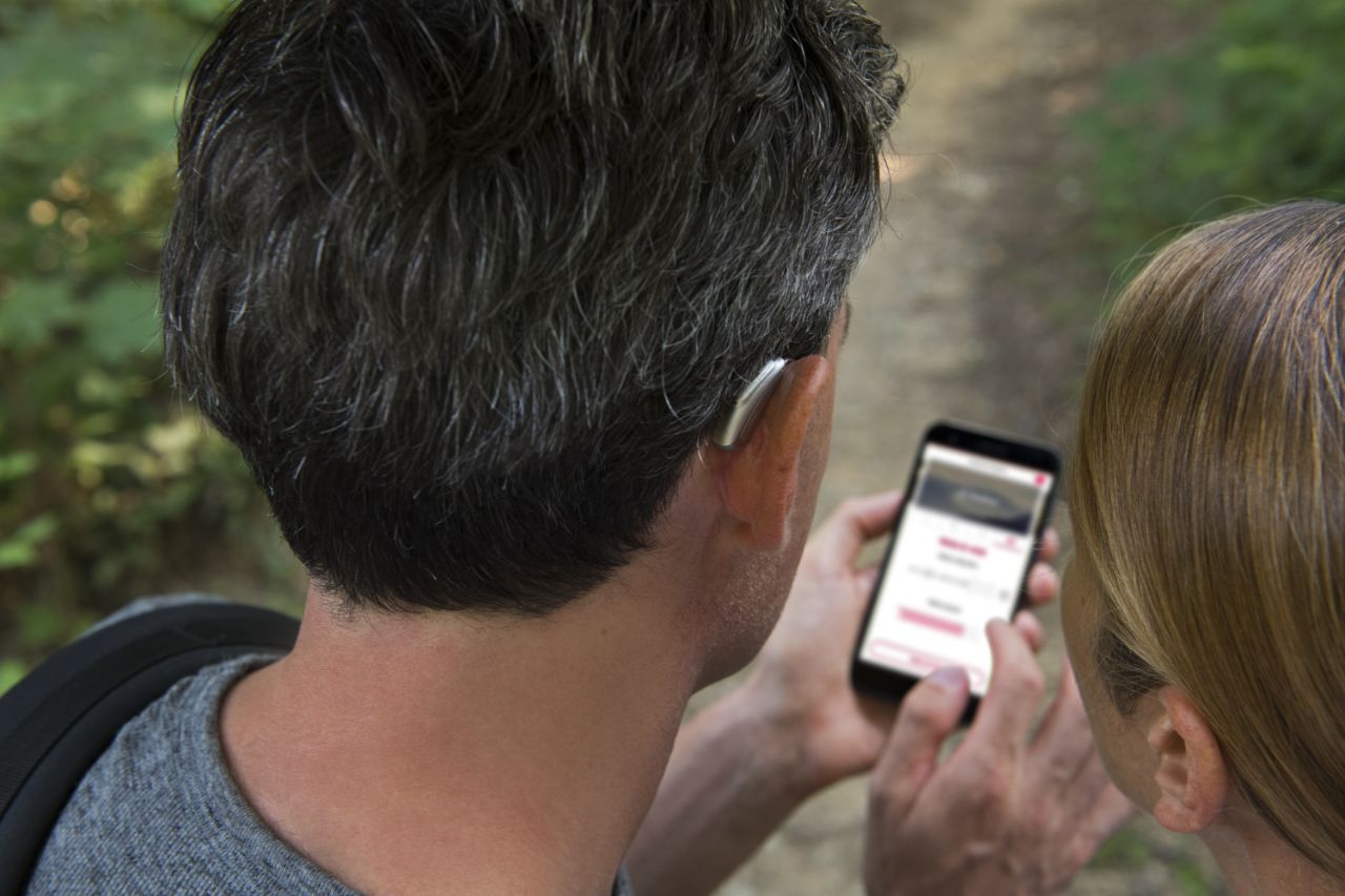 Un homme portant un appareil auditif utilisant une application sur son téléphone