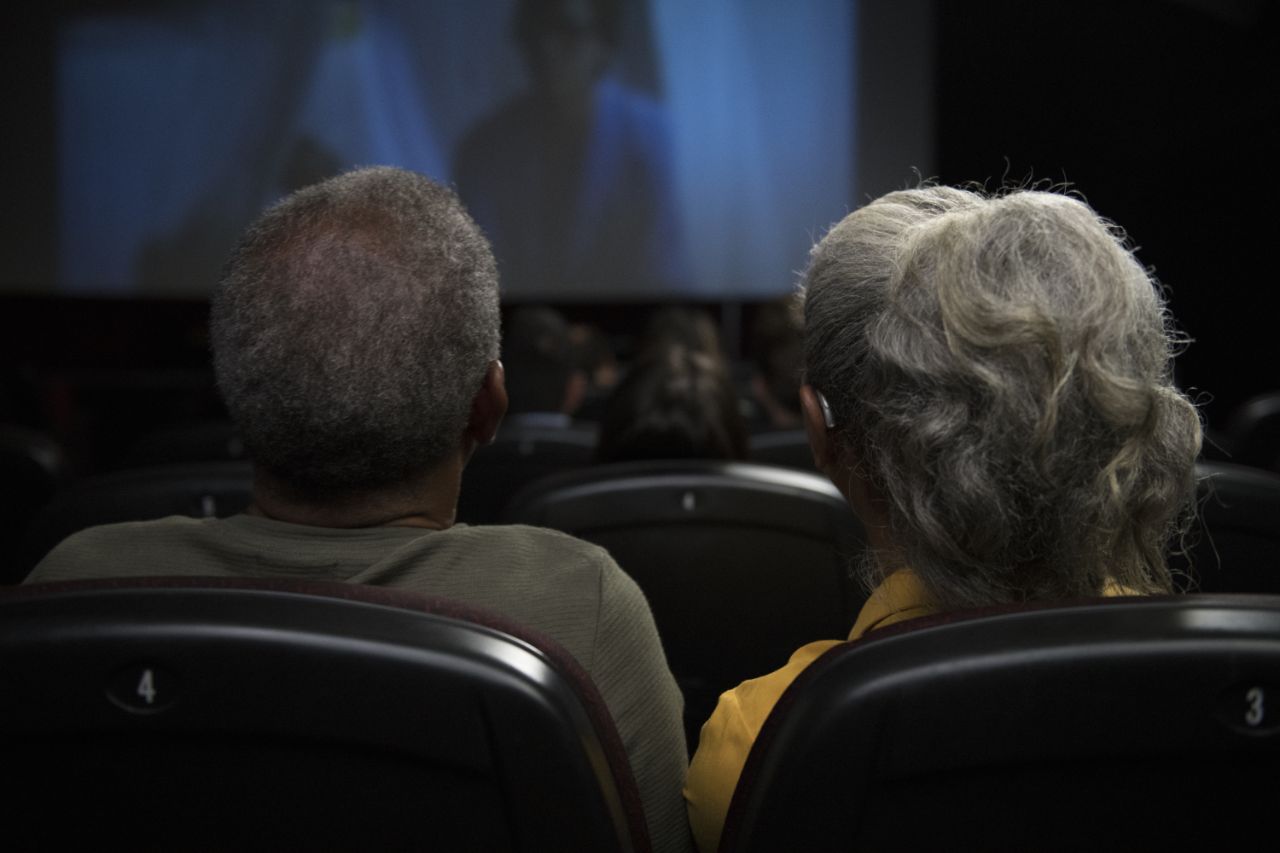 Une femme senior portant un appareil auditif au théâtre avec son compagnon