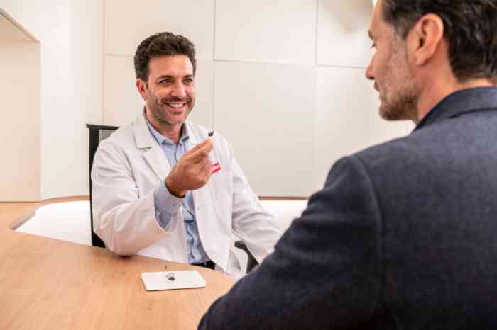 Man with Behind-The-Ear hearing aid looking at Amplifon app