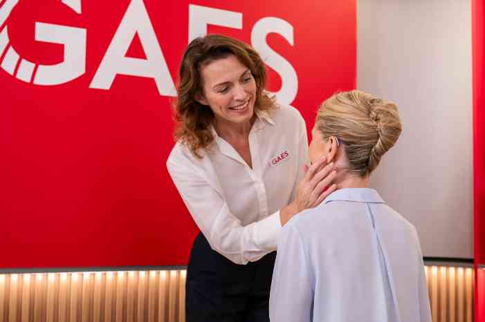 Audiologist inserting hearing aid in client's ear