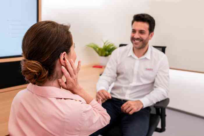 Un expert d'Amplifon salue et remercie deux clients qui quittent le magasin.