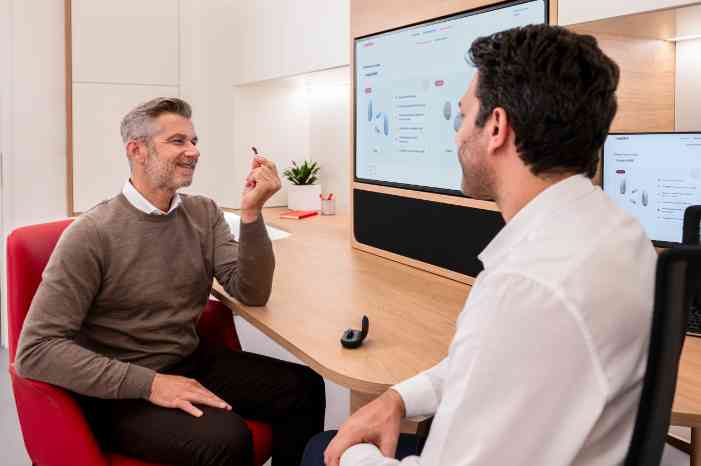 Audiologist and a client holdin a hearing aid