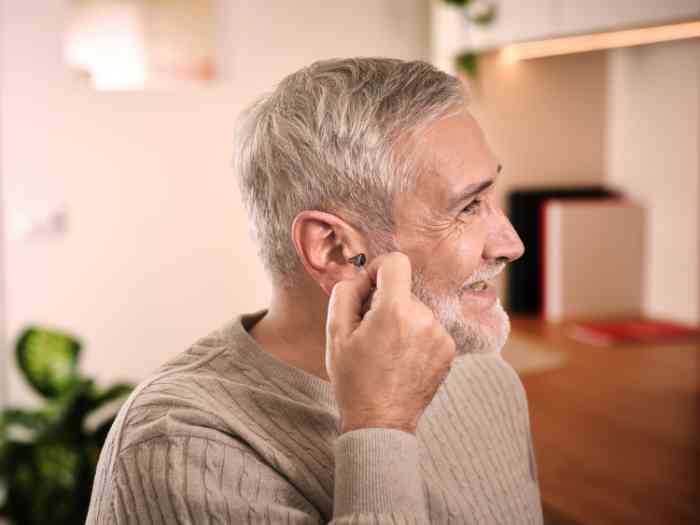 uomo che posiziona un apparecchio acustico ampli mini.