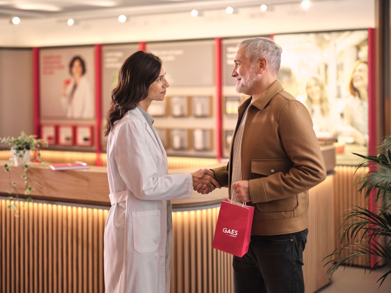 homme saluant l'audiologiste en blouse dans un magasin Gaes.