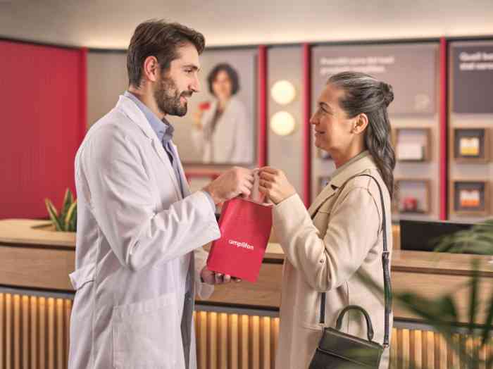 Frau verabschiedet sich vom Audiologen mit Kittel in einem Amplifon-Geschäft.