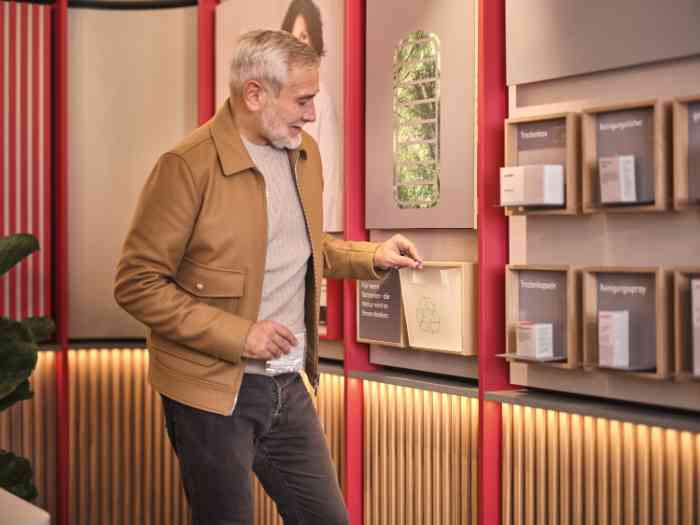 Ein Mann recycelt alte Batterien in einem geeigneten Container in einem deutschen Geschäft.