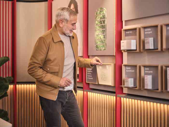 un uomo che ricicla vecchie batterie in un contenitore apposito in un negozio in italia.