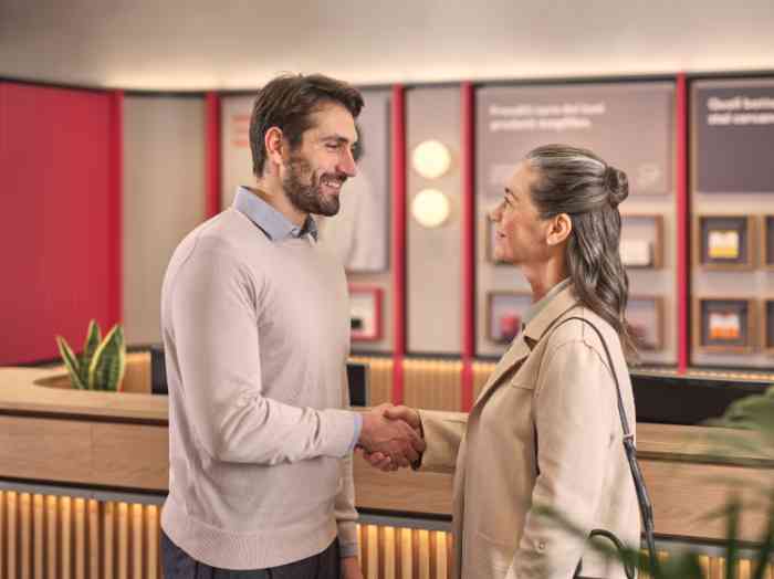 Audiologe ohne Laborkittel begrüßt ein Paar im Geschäft.