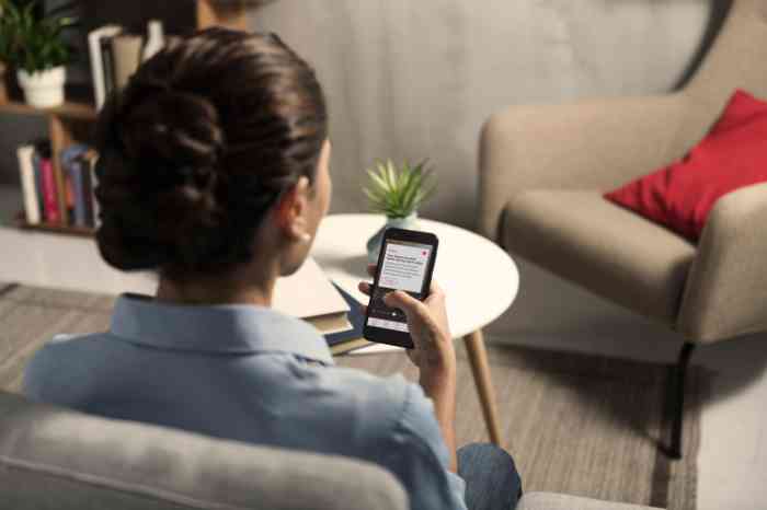 A girl with Behind-The-Ear hearing aid looking at her smartphone