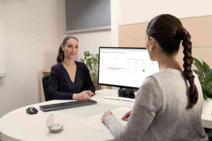 Una donna con apparecchio acustico BTE che parla con una professionista Amplifon.