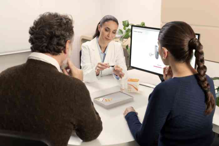Amplifon's audiologist showing a pair of Behind-The-Ear hearing aids to customers
