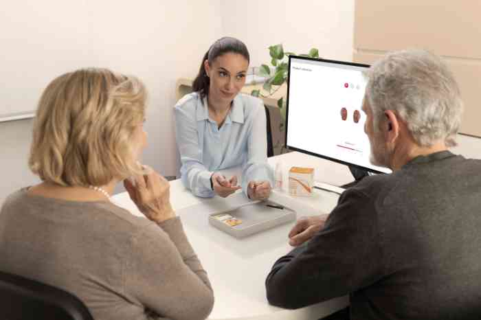 Experte Amplifon expliquant les piles et les produits de nettoyage à un couple âgé